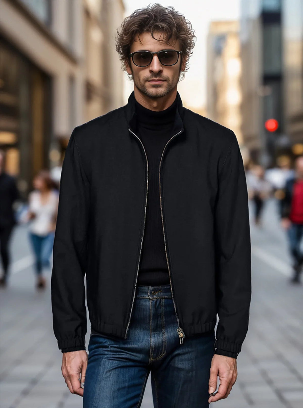 Man wearing a black jacket, black turtleneck, and blue jeans on a city street.
