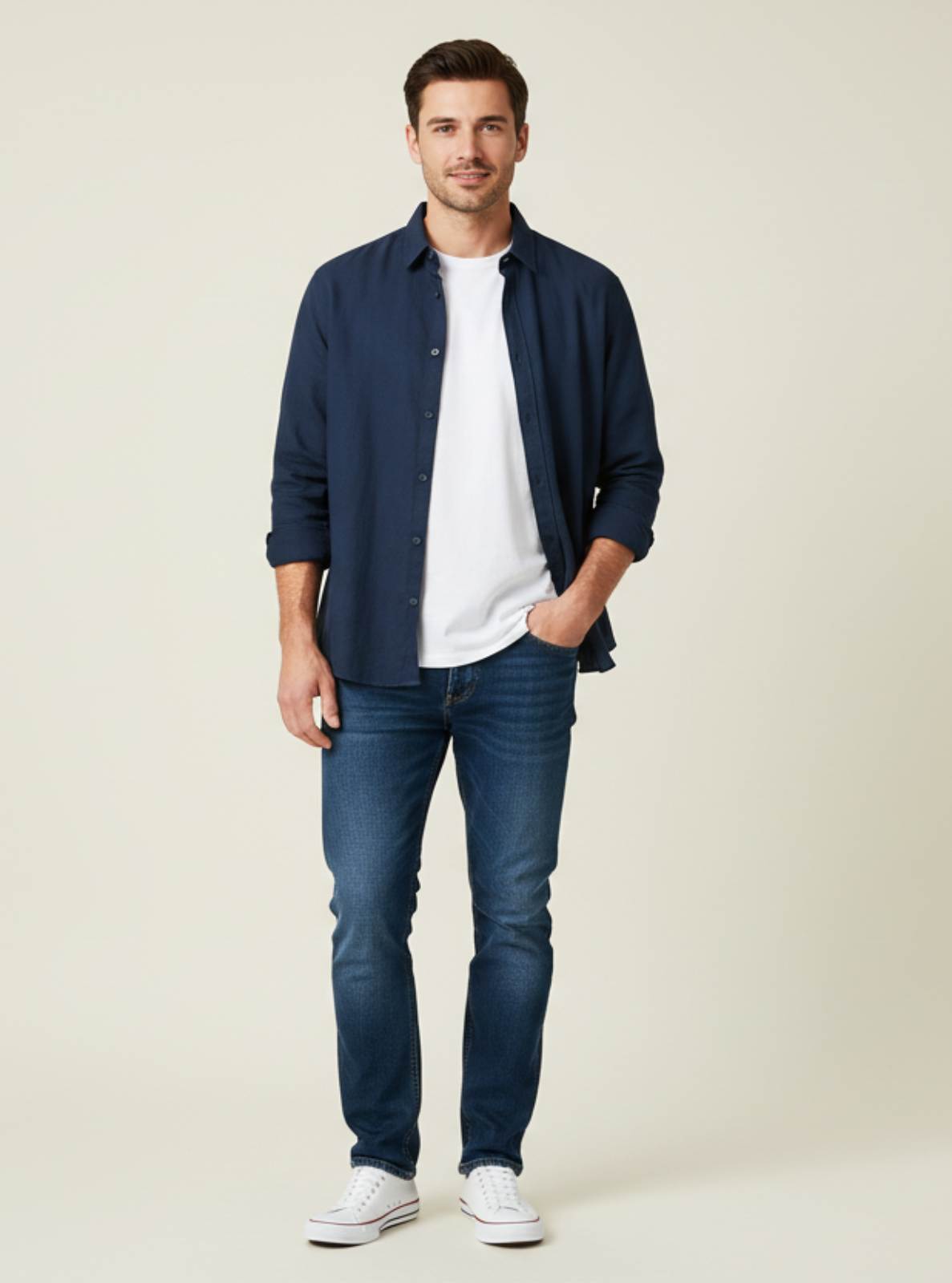 Man wearing a navy jacket, white shirt, and jeans on a beige background
