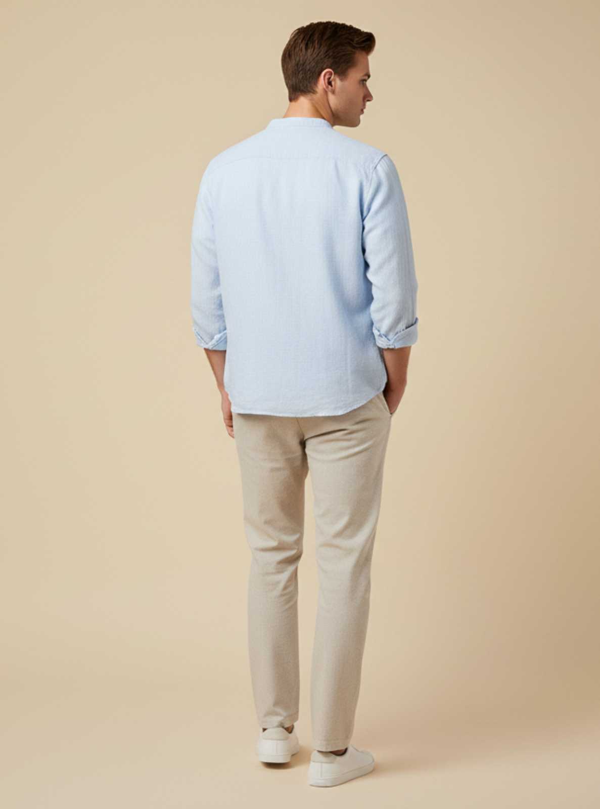 Man wearing a light blue shirt and beige pants against a beige background