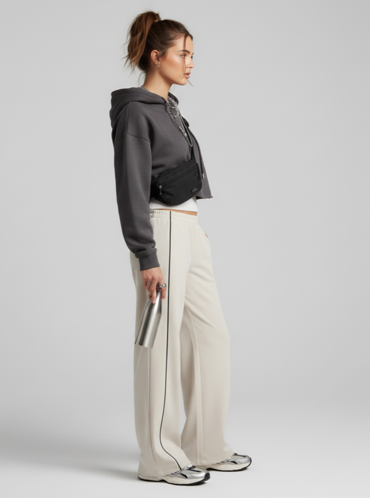 Person wearing a gray hoodie and white pants on a plain background