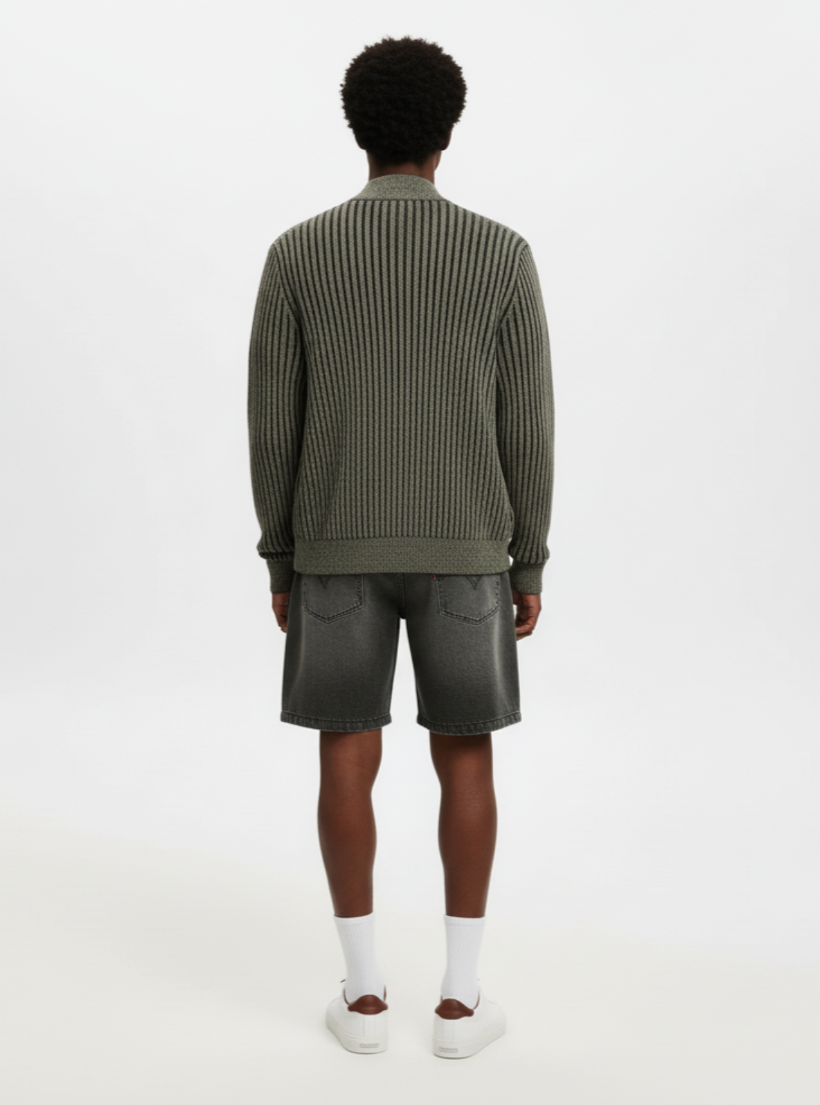 Person wearing a green ribbed sweater and shorts on a white background
