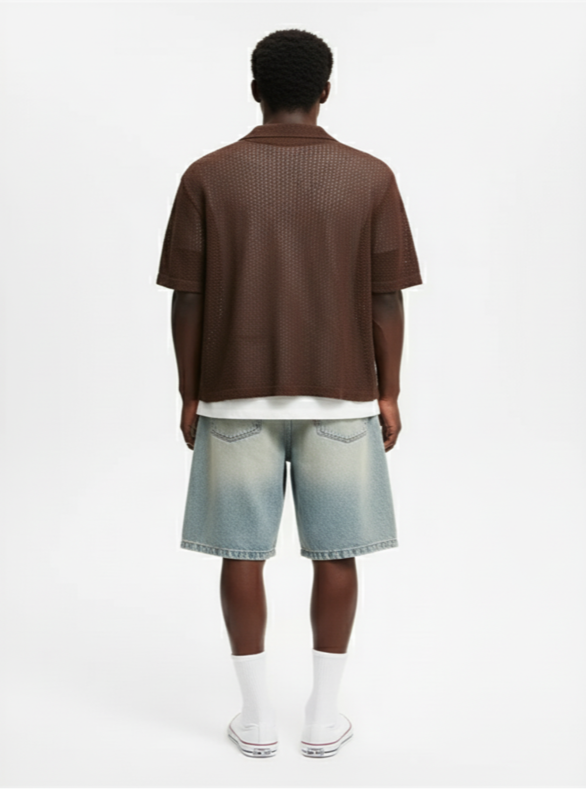 Person wearing a brown shirt and denim shorts on a white background