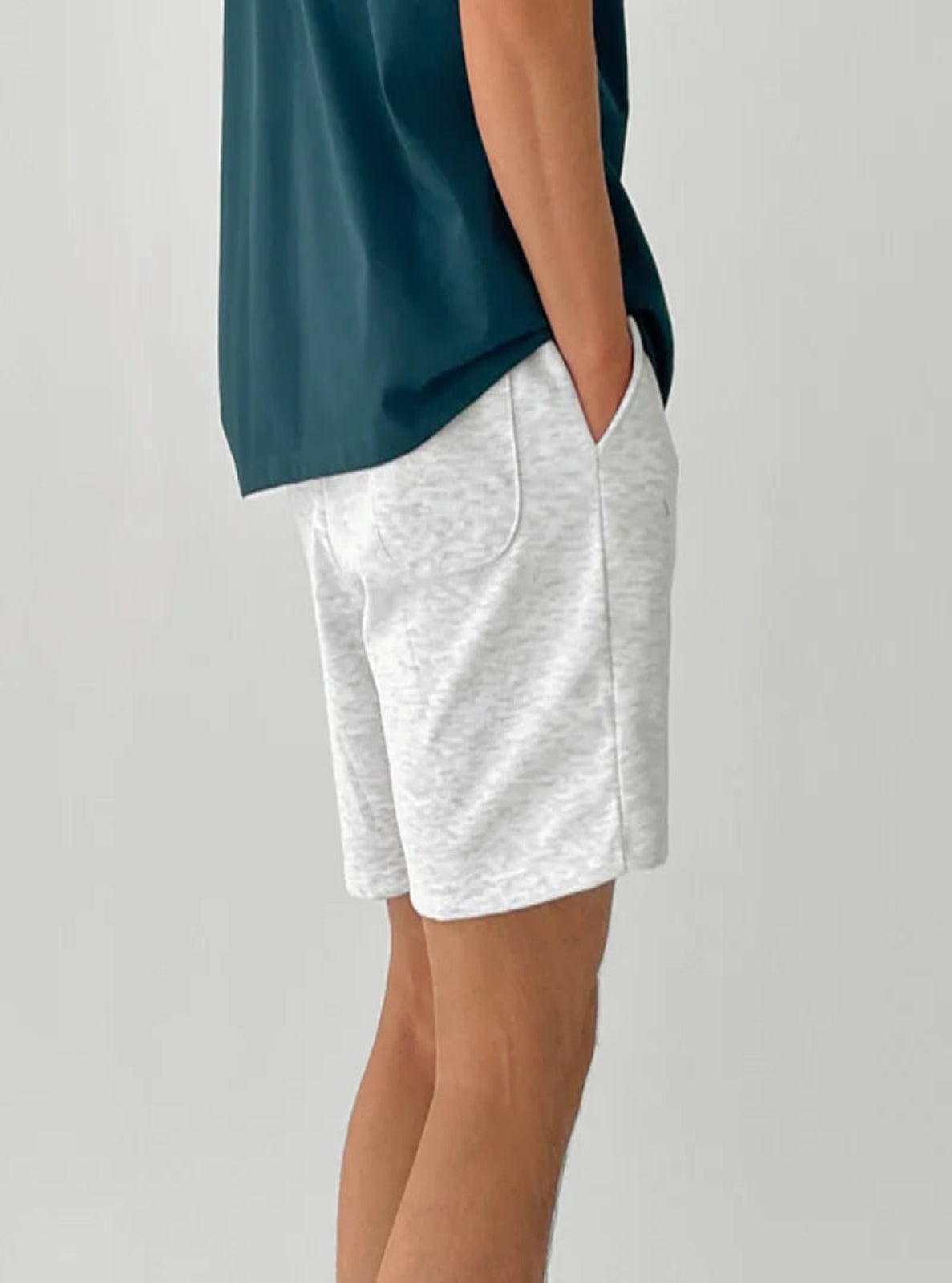 Person wearing white shorts and a dark green top on a light gray background