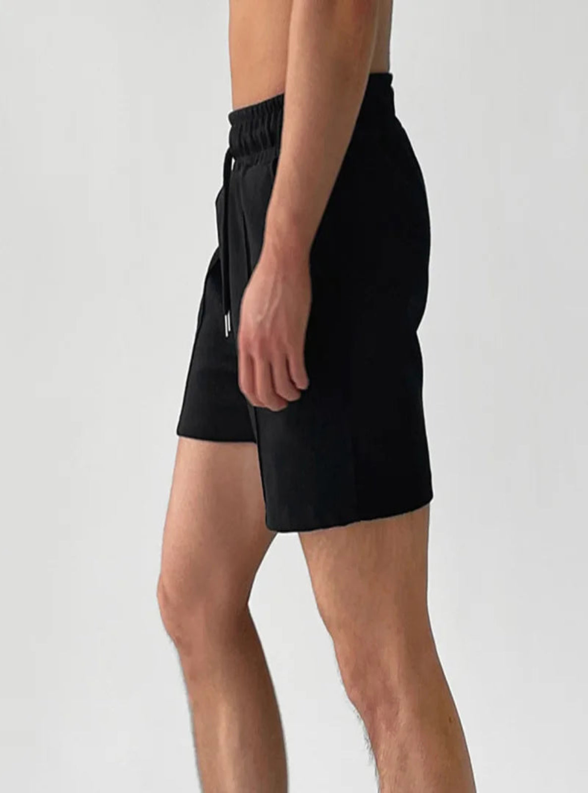 Person wearing black shorts on a plain background