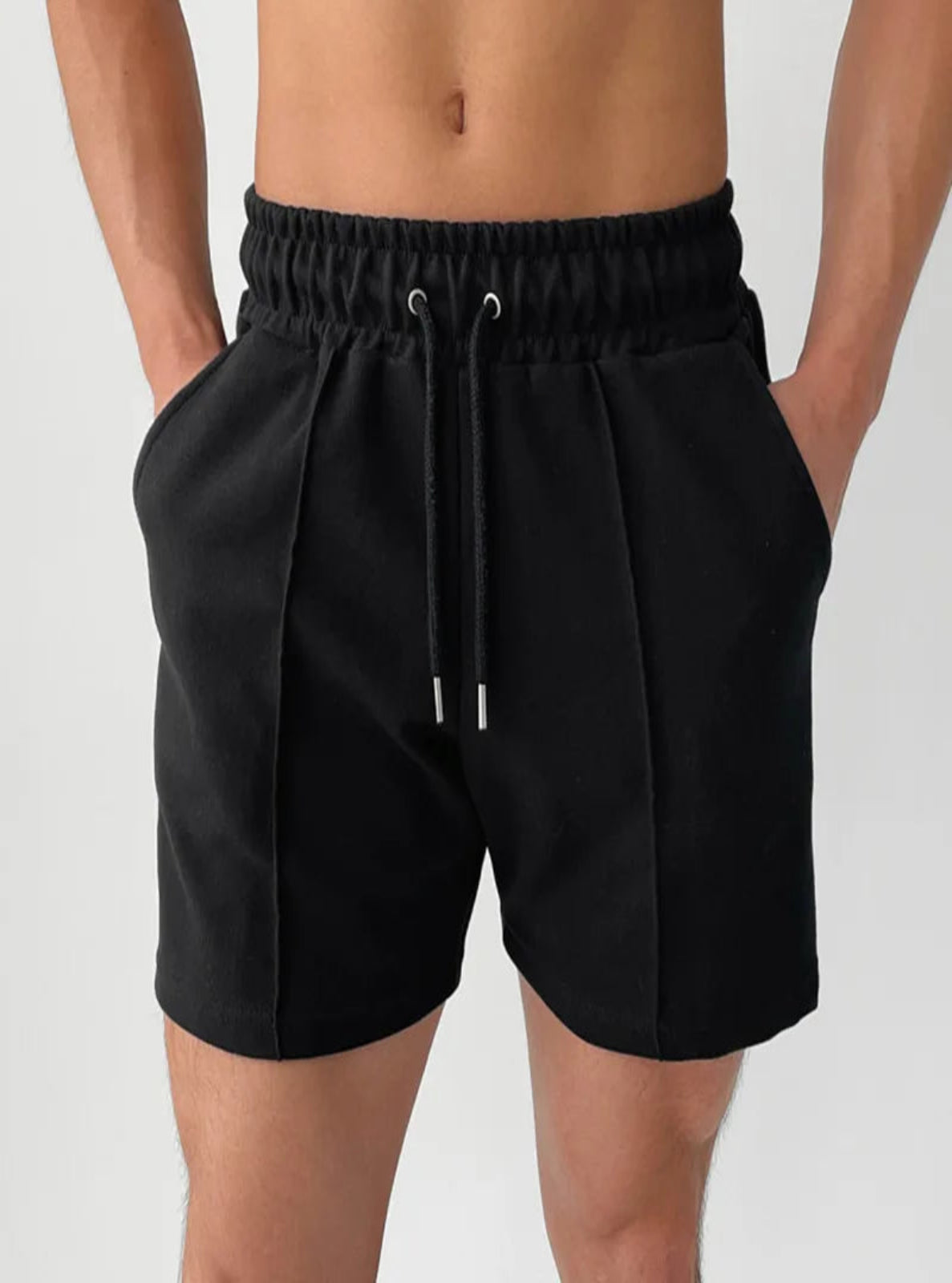 Black shorts worn by a person on a plain background