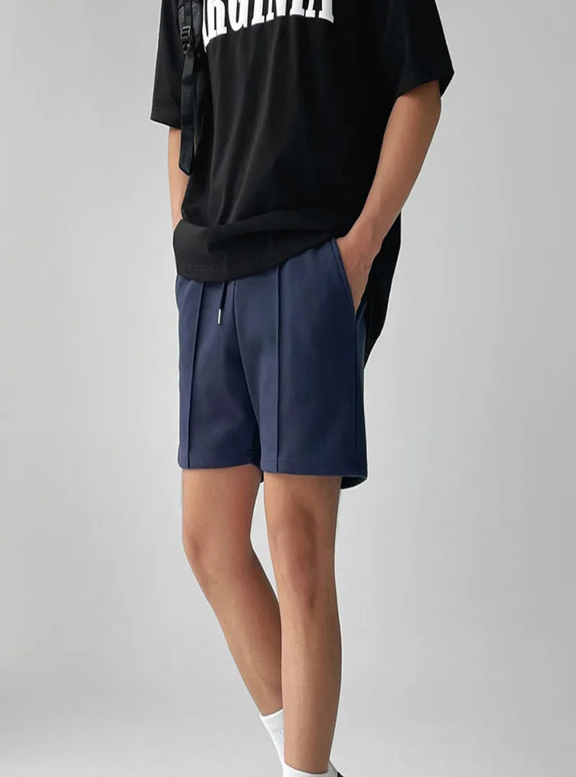 Person wearing navy shorts and a black t-shirt with white text on a plain background