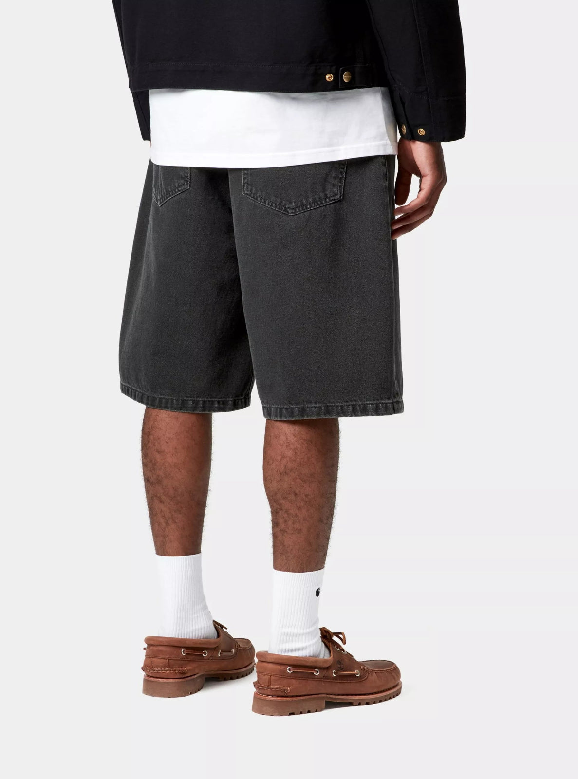 Person wearing black shorts, white socks, and brown shoes on a white background
