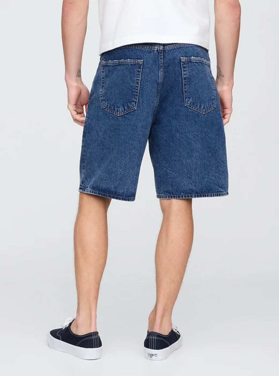 Person wearing blue denim shorts on a white background