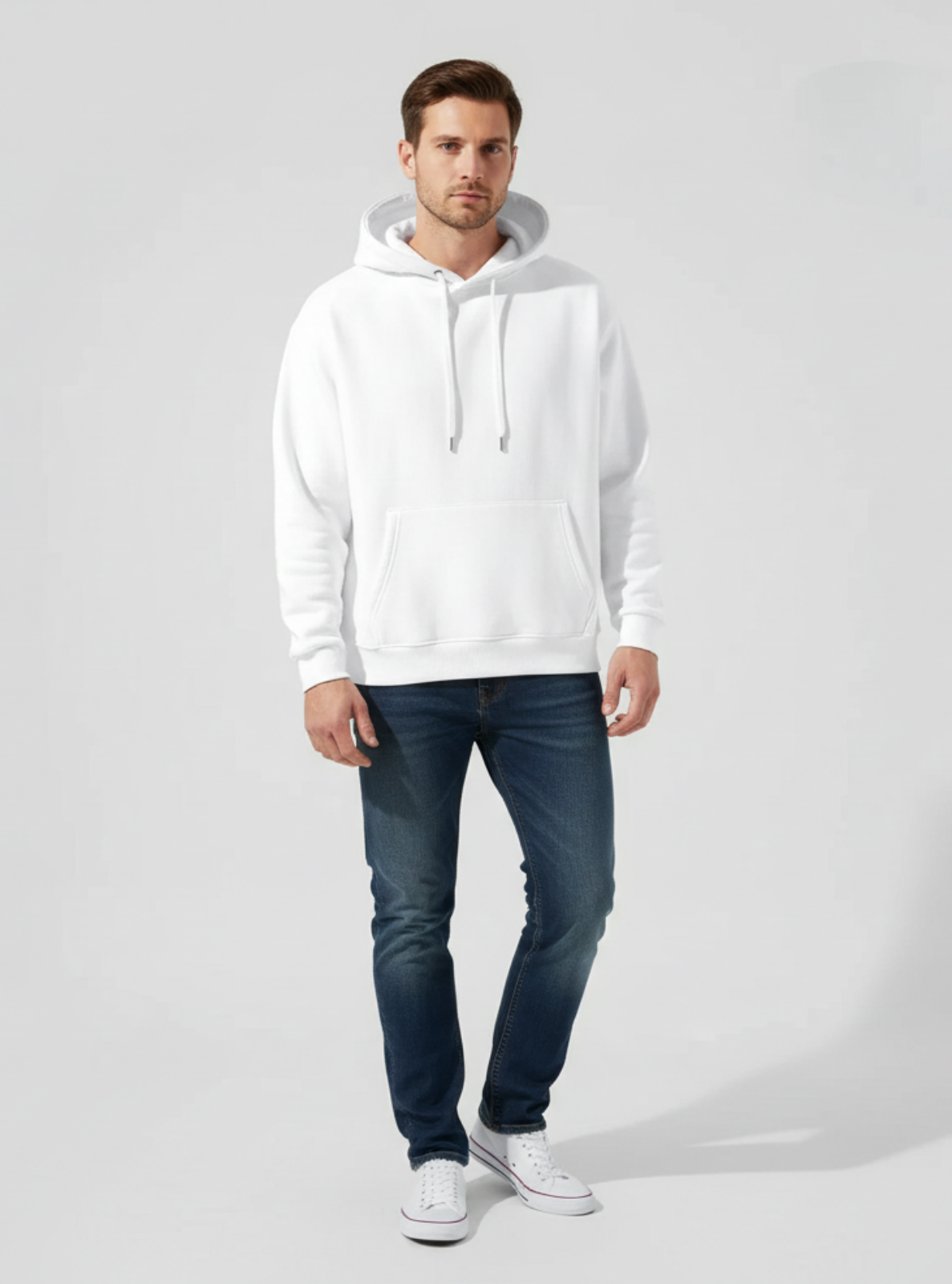 Man wearing a white hoodie and blue jeans on a gray background