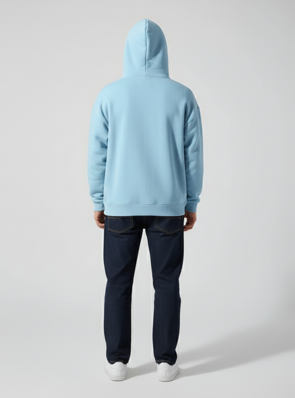 Person wearing a light blue hoodie and dark pants on a plain background