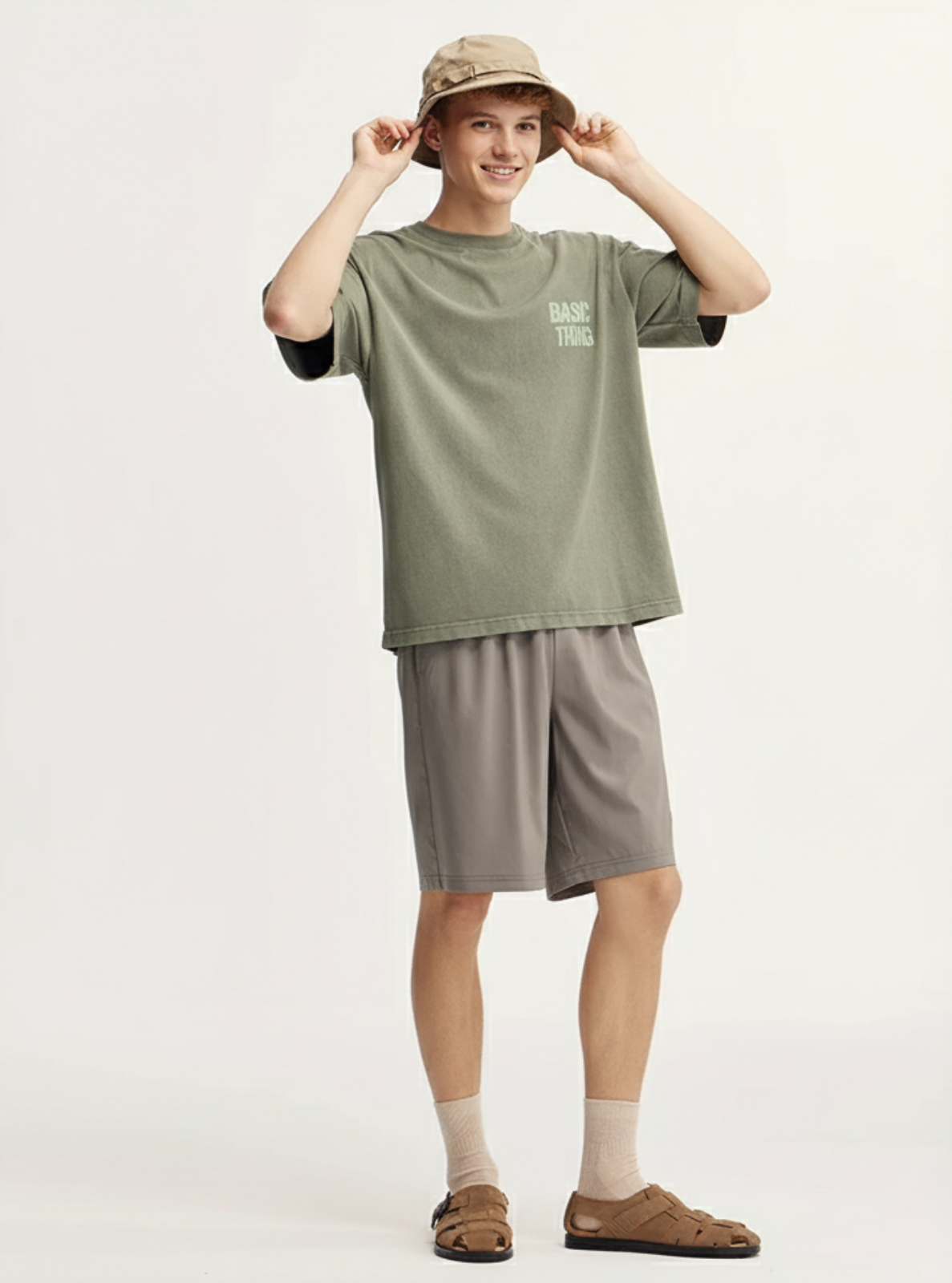 Person wearing a green t-shirt and gray shorts on a white background