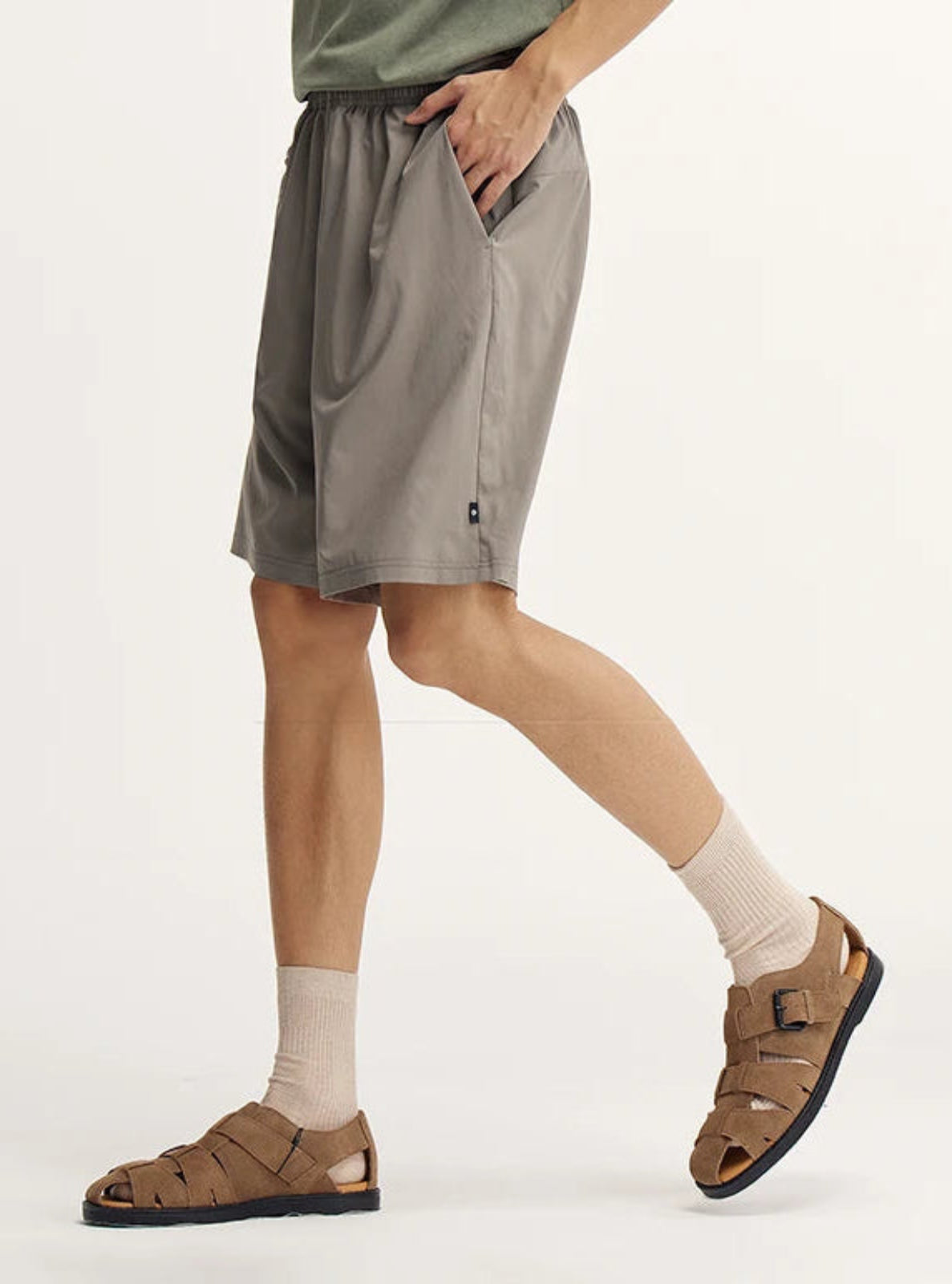 Person wearing gray shorts, white socks, and brown sandals on a white background