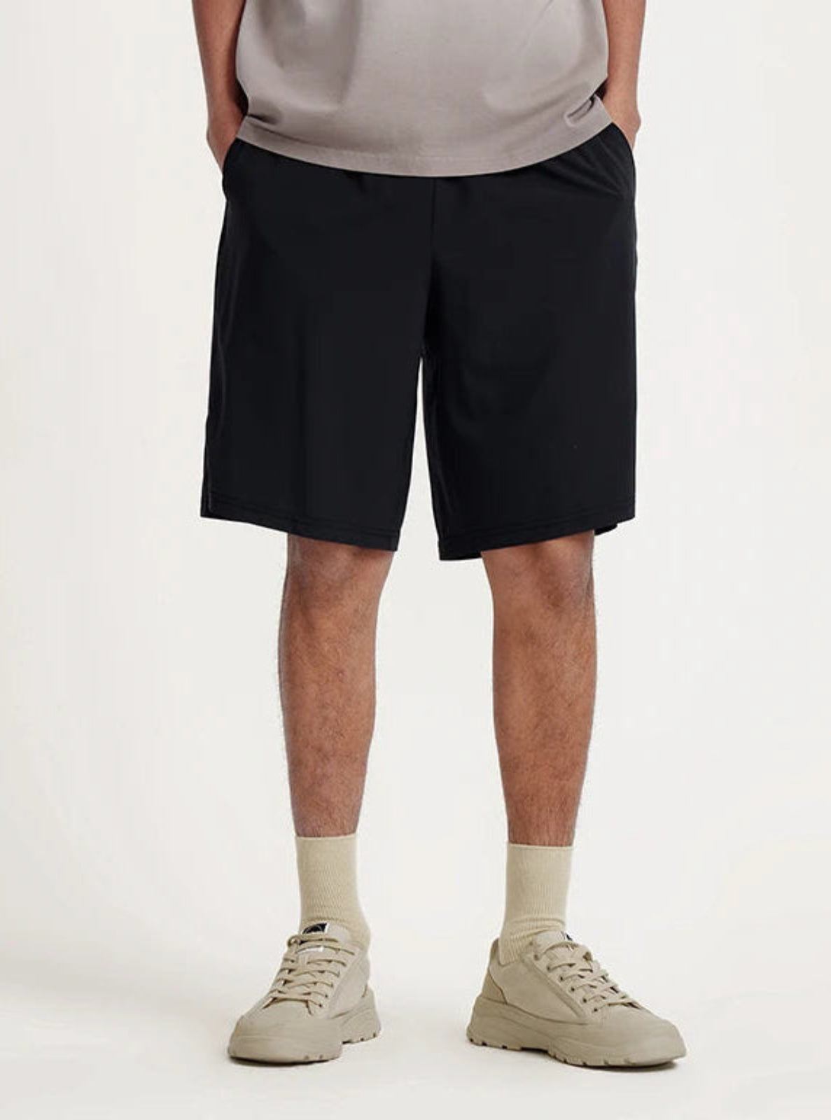 Person wearing black shorts and beige shoes on a white background