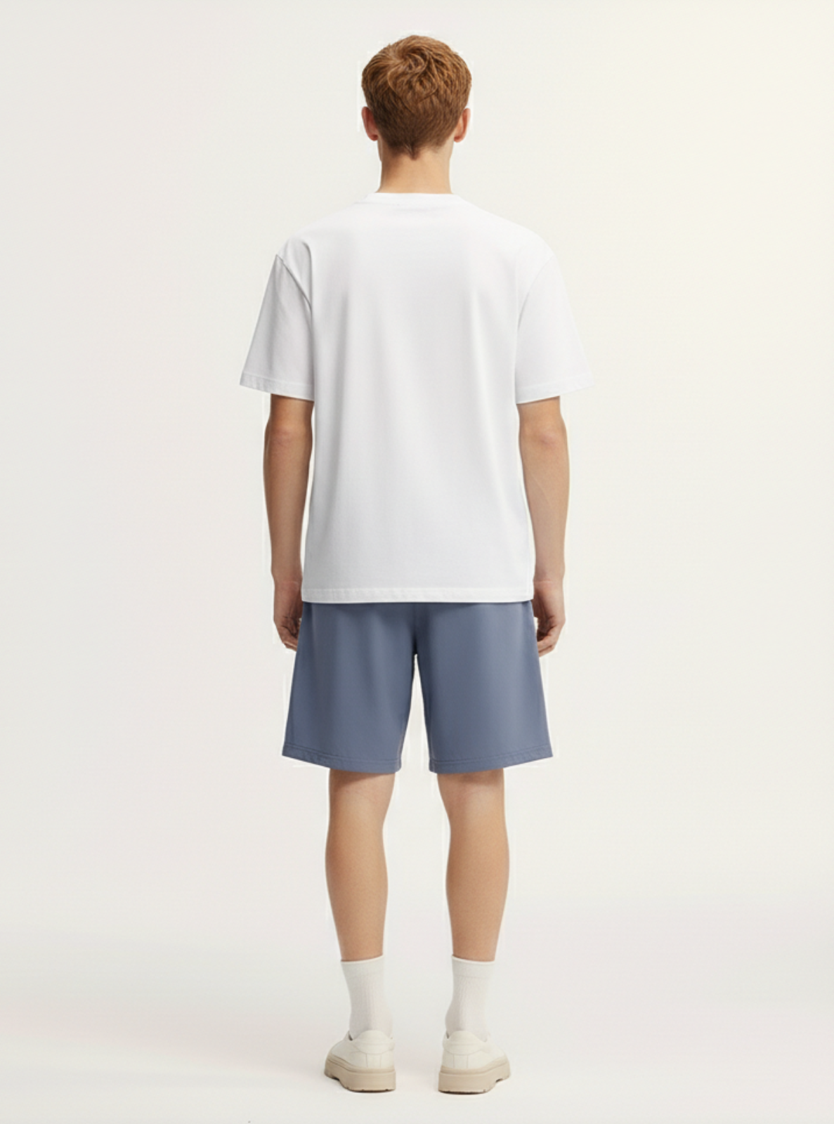 Person wearing a white t-shirt and blue shorts on a plain background