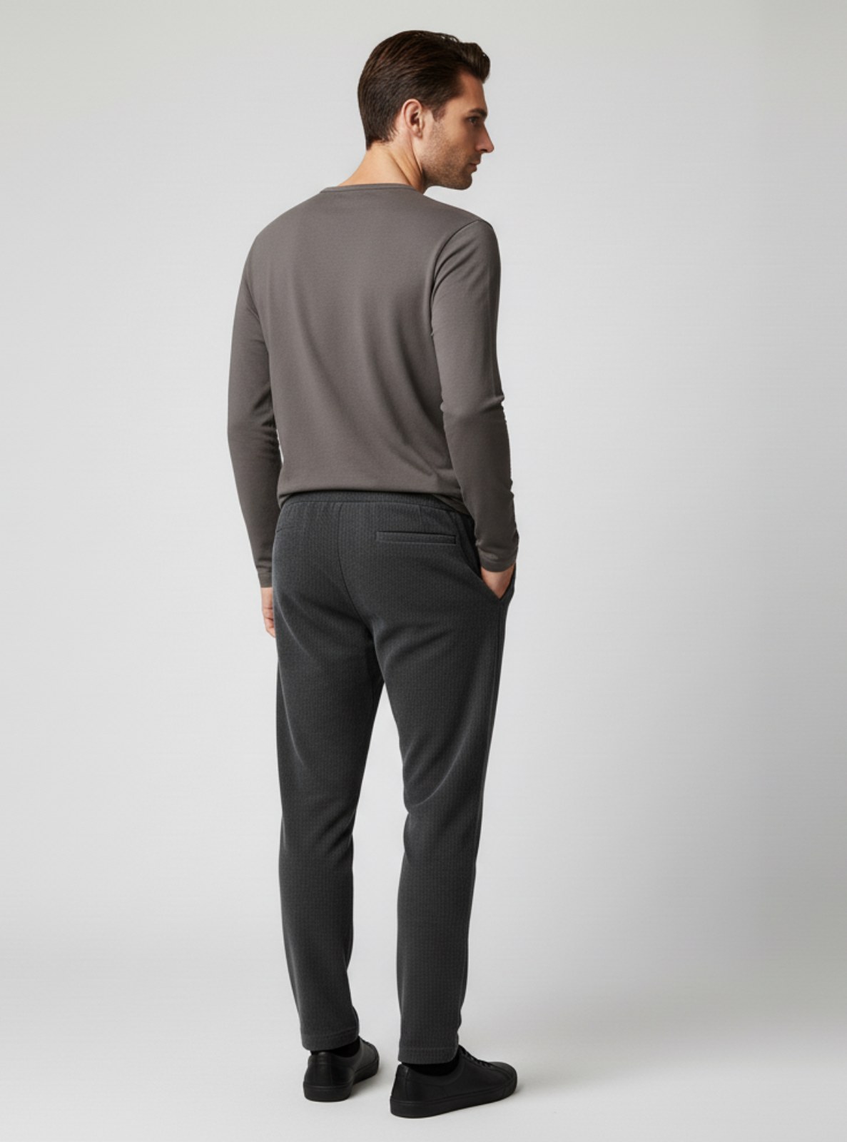 Man wearing a gray long-sleeve shirt and dark gray pants on a white background