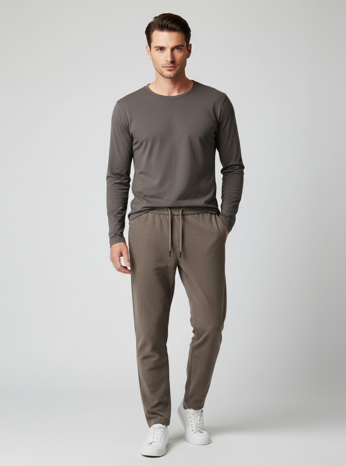Man wearing a gray long-sleeve shirt and brown pants on a white background