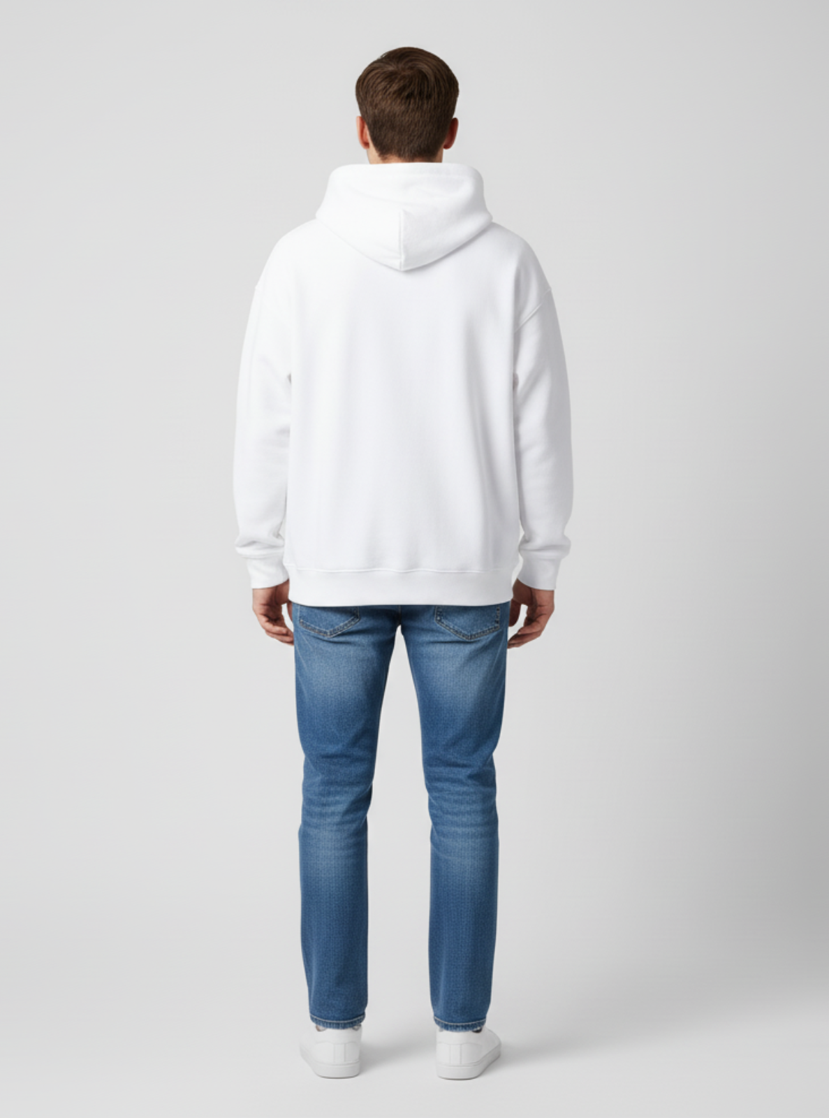 Person wearing a white hoodie and blue jeans on a light gray background