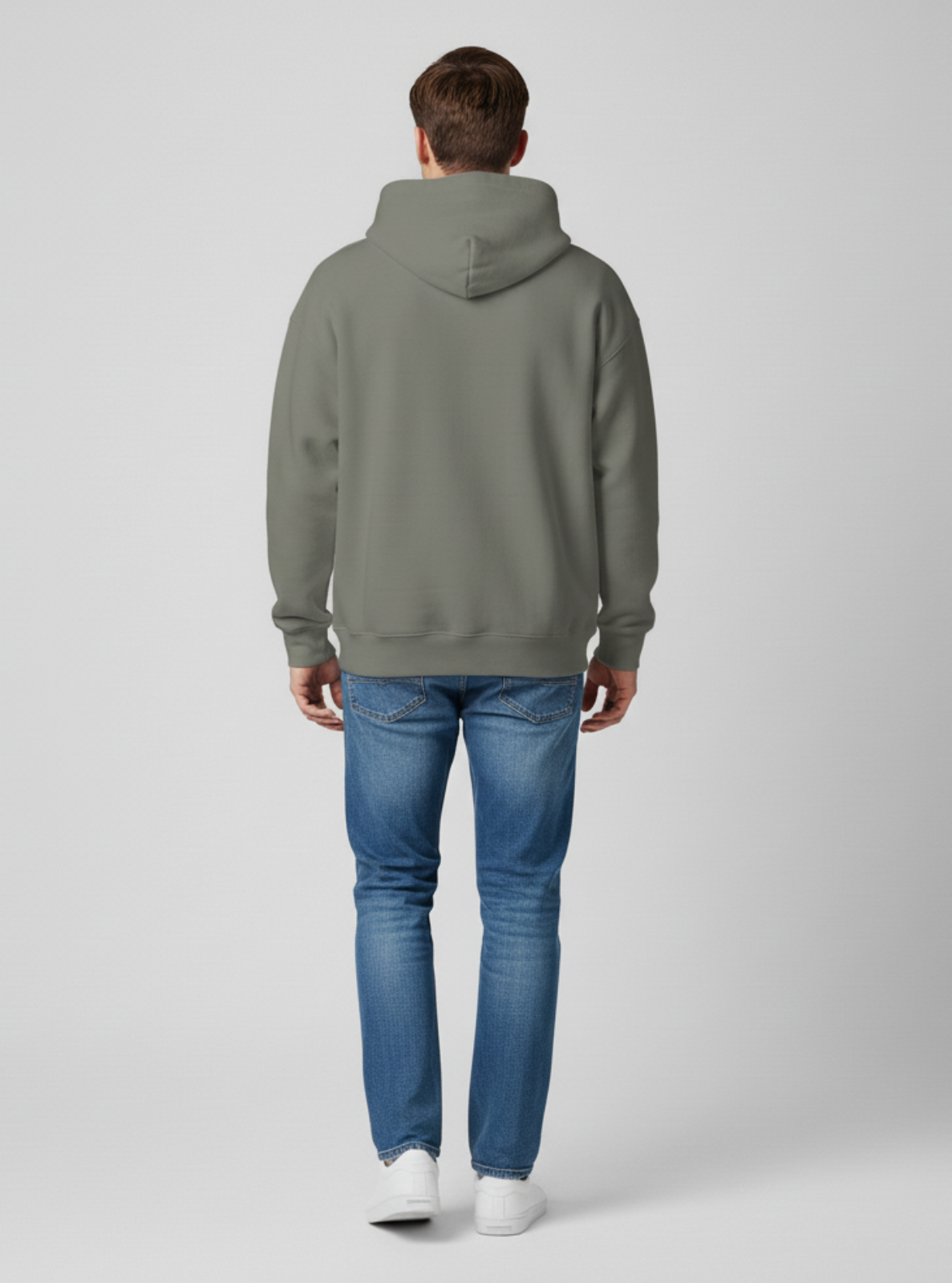 Person wearing a gray hoodie and blue jeans on a white background