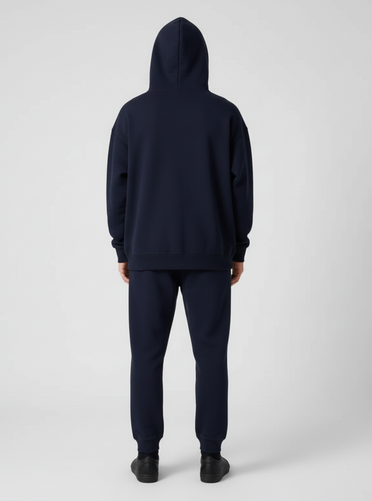 Person wearing a navy blue hoodie and pants on a white background