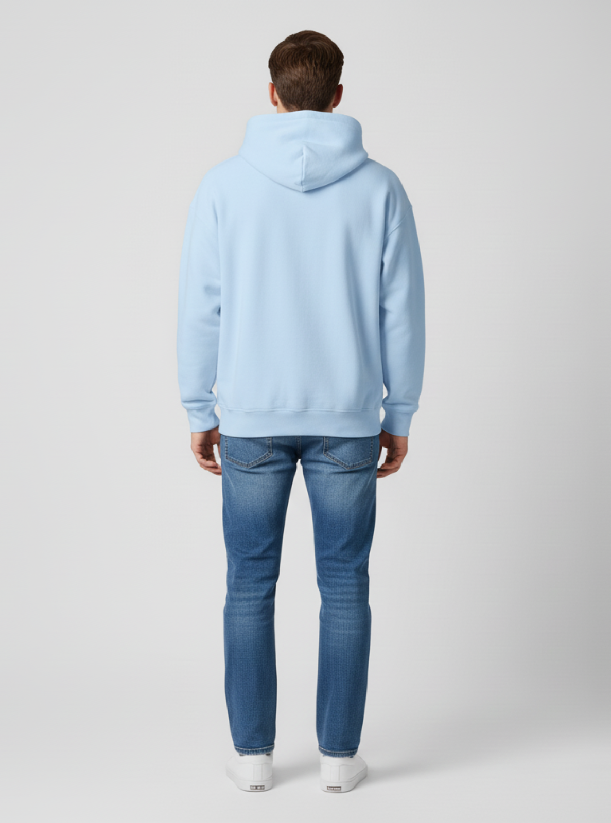 Person wearing a light blue hoodie and jeans on a white background