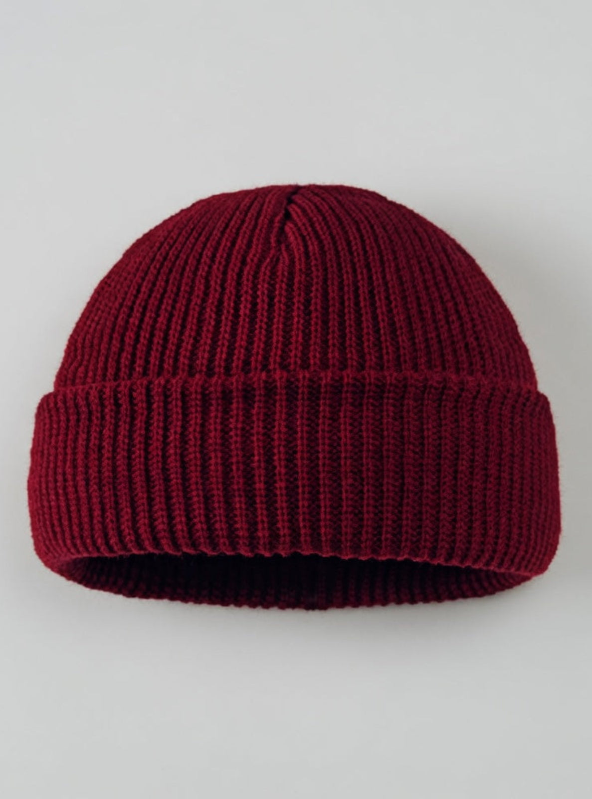 Maroon knit beanie on a light gray background