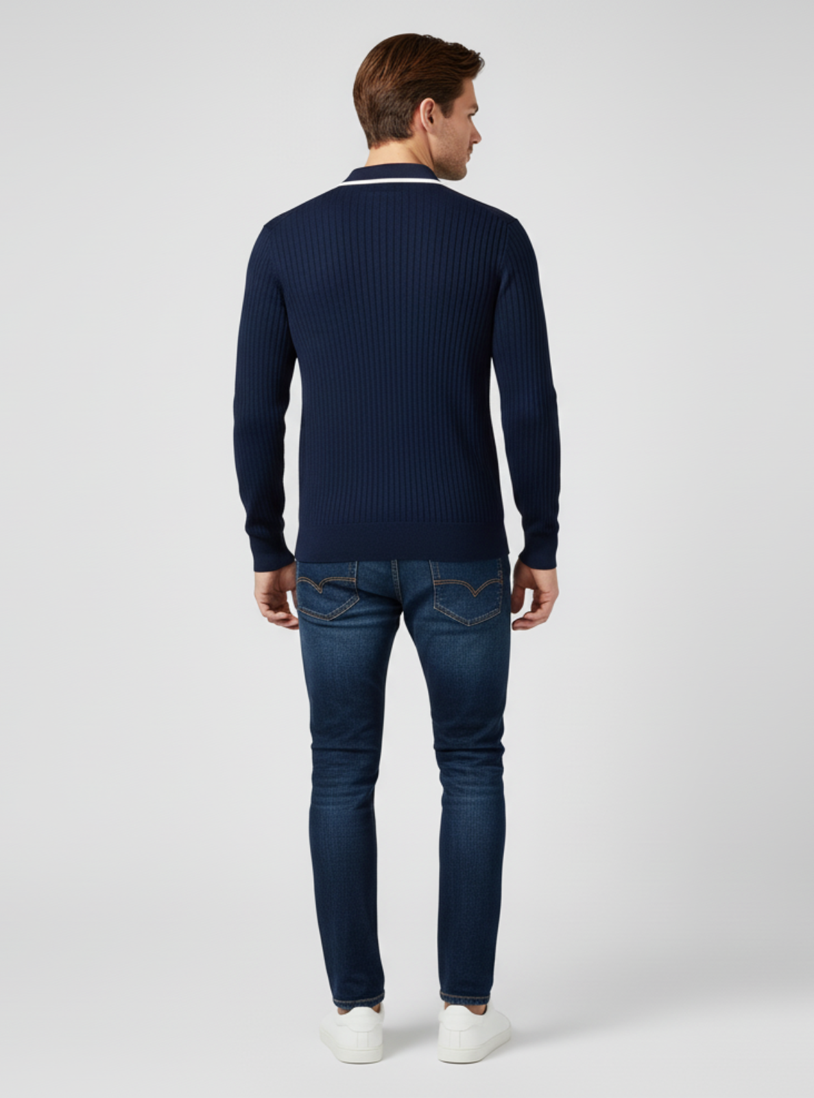 Man wearing a navy sweater and jeans on a white background