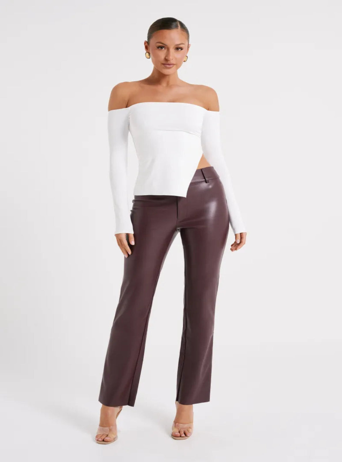 Woman wearing a white off-shoulder top and brown pants on a white background