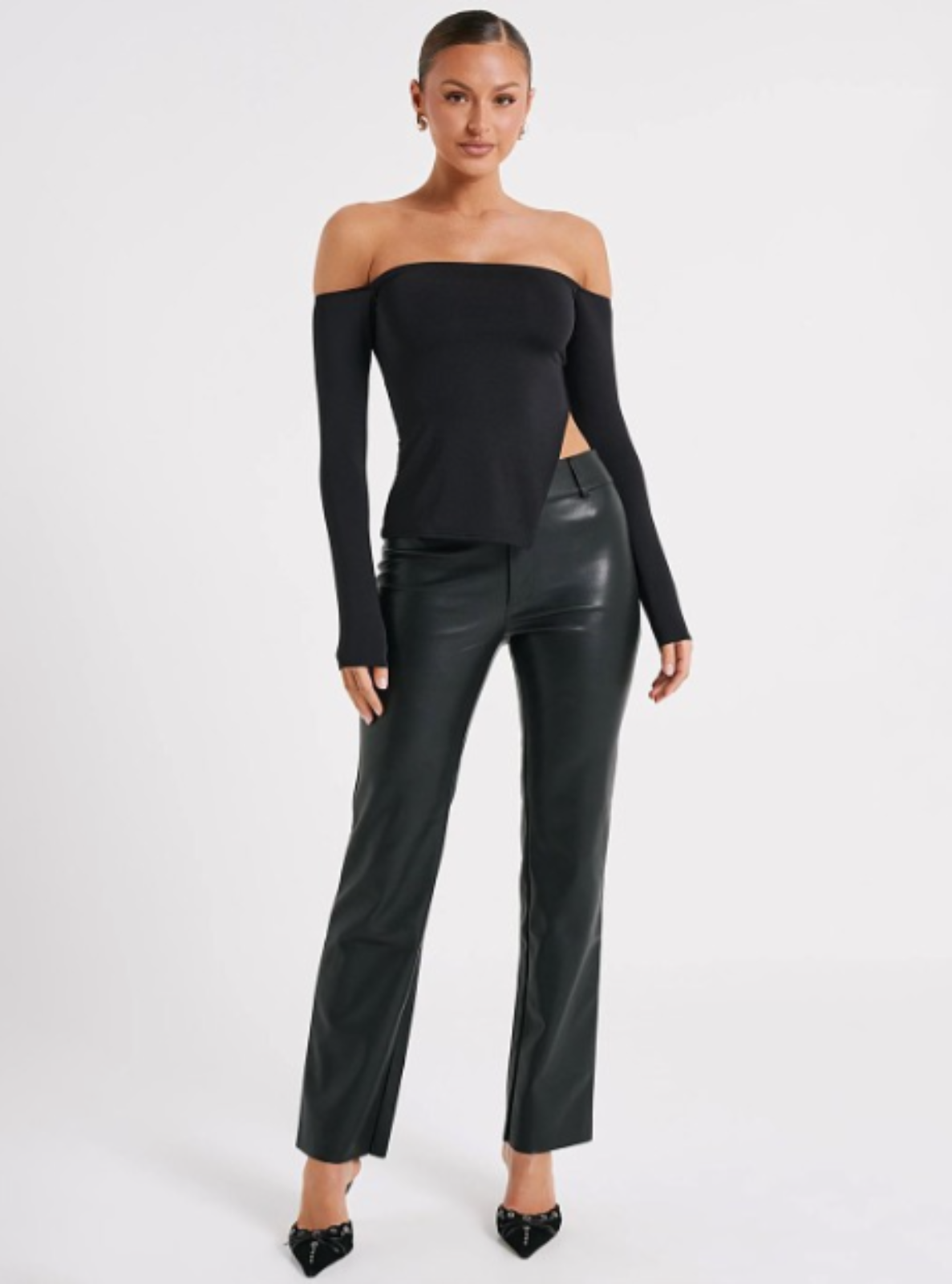 Woman wearing a black off-shoulder top and black leather pants on a white background