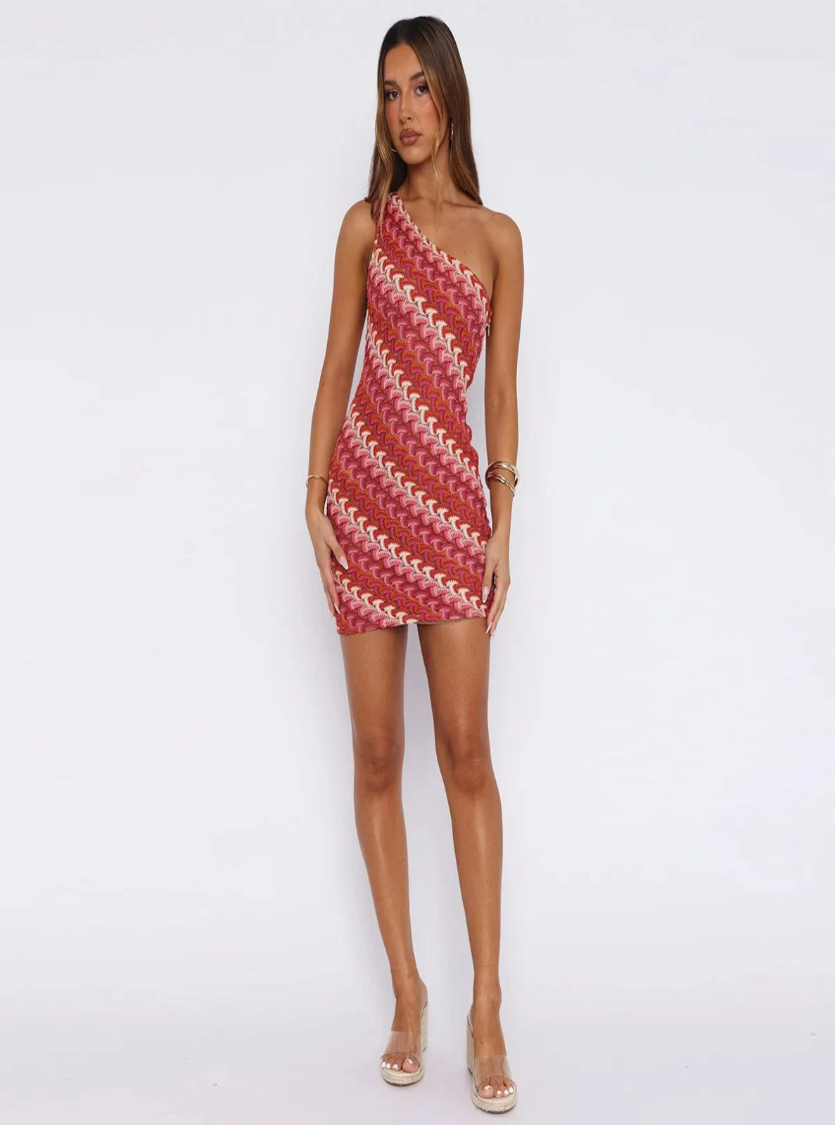 Woman wearing a red and white patterned one-shoulder dress on a white background