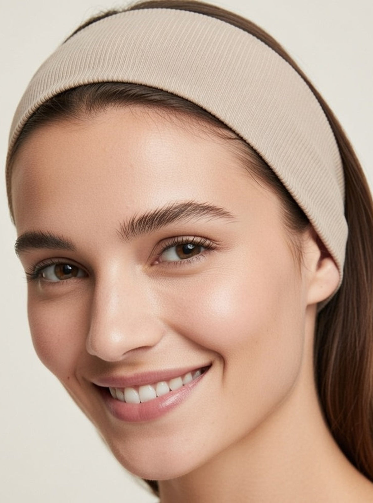 Woman wearing a beige headband against a plain background