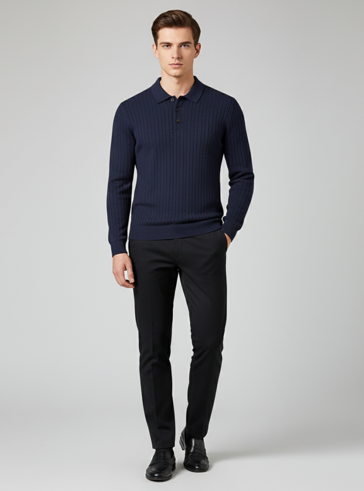 Man wearing a navy ribbed sweater and black pants on a gray background