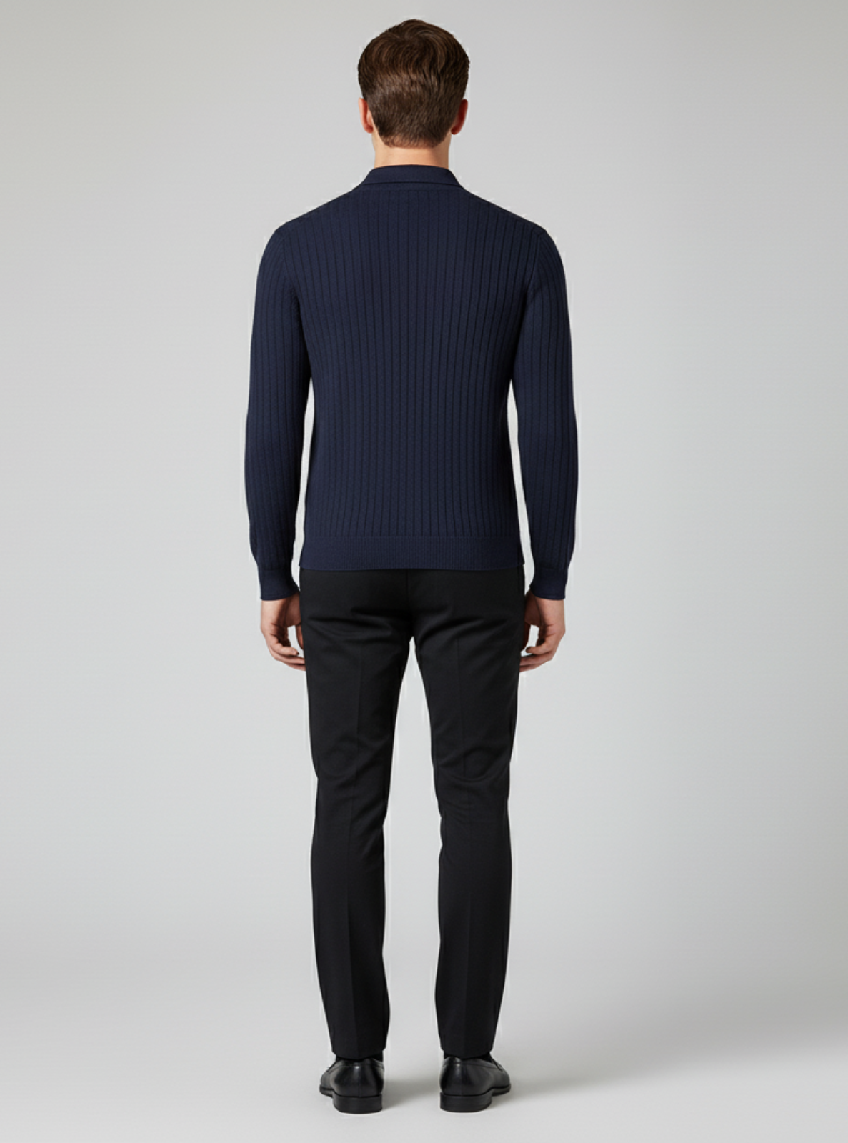 Man wearing a navy ribbed sweater and black pants on a light gray background