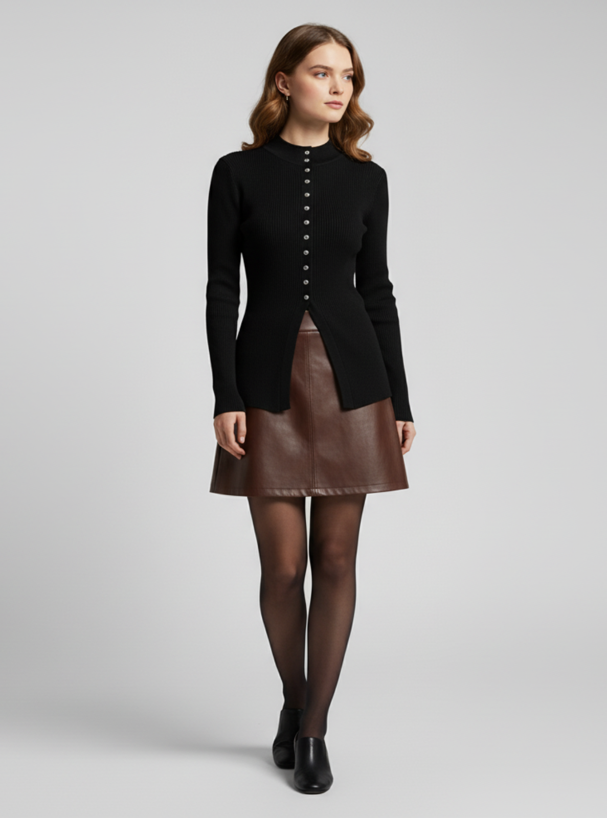 Woman wearing a black jacket and brown leather skirt on a gray background