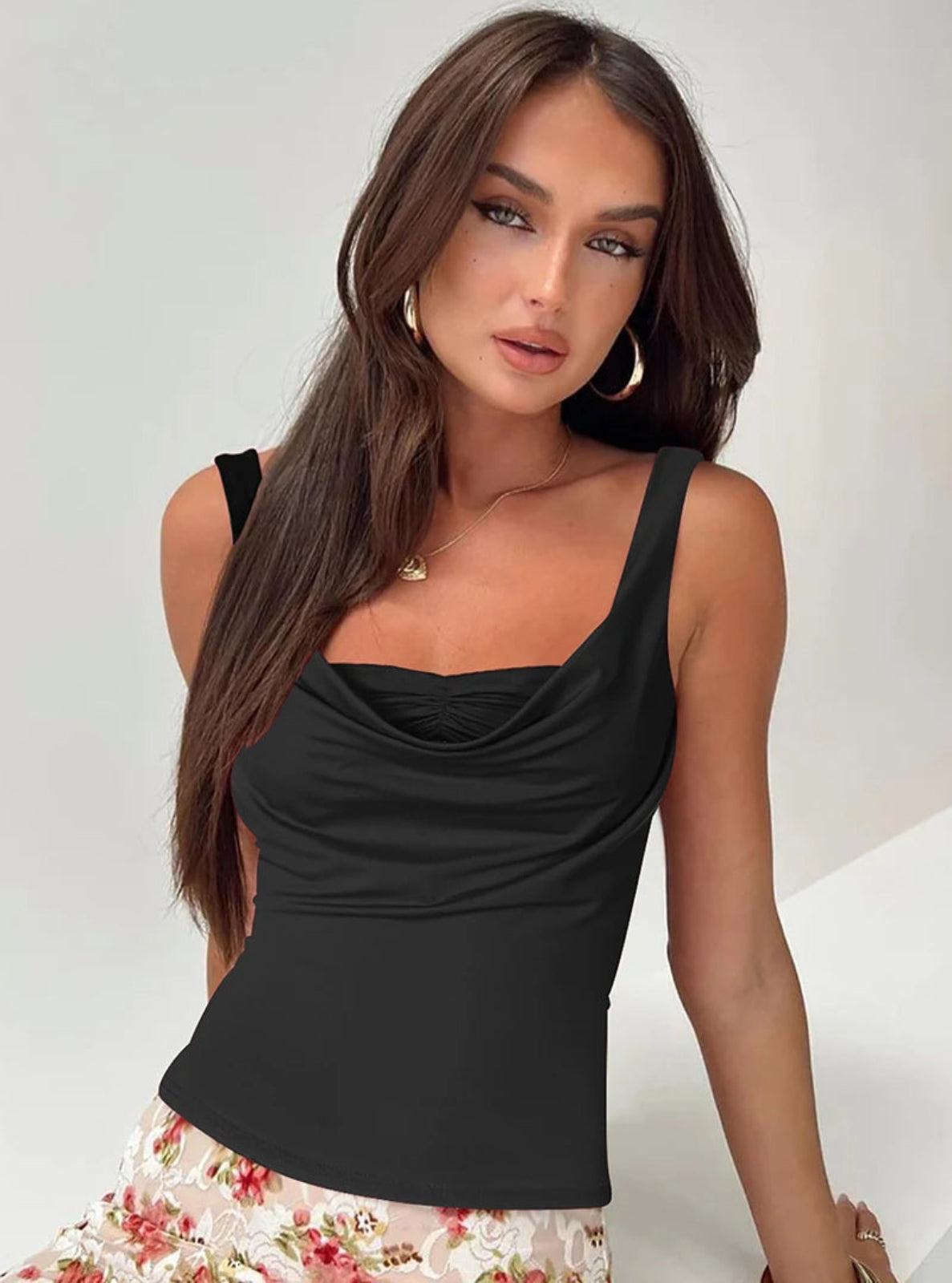 Woman wearing a black sleeveless top with a plain background