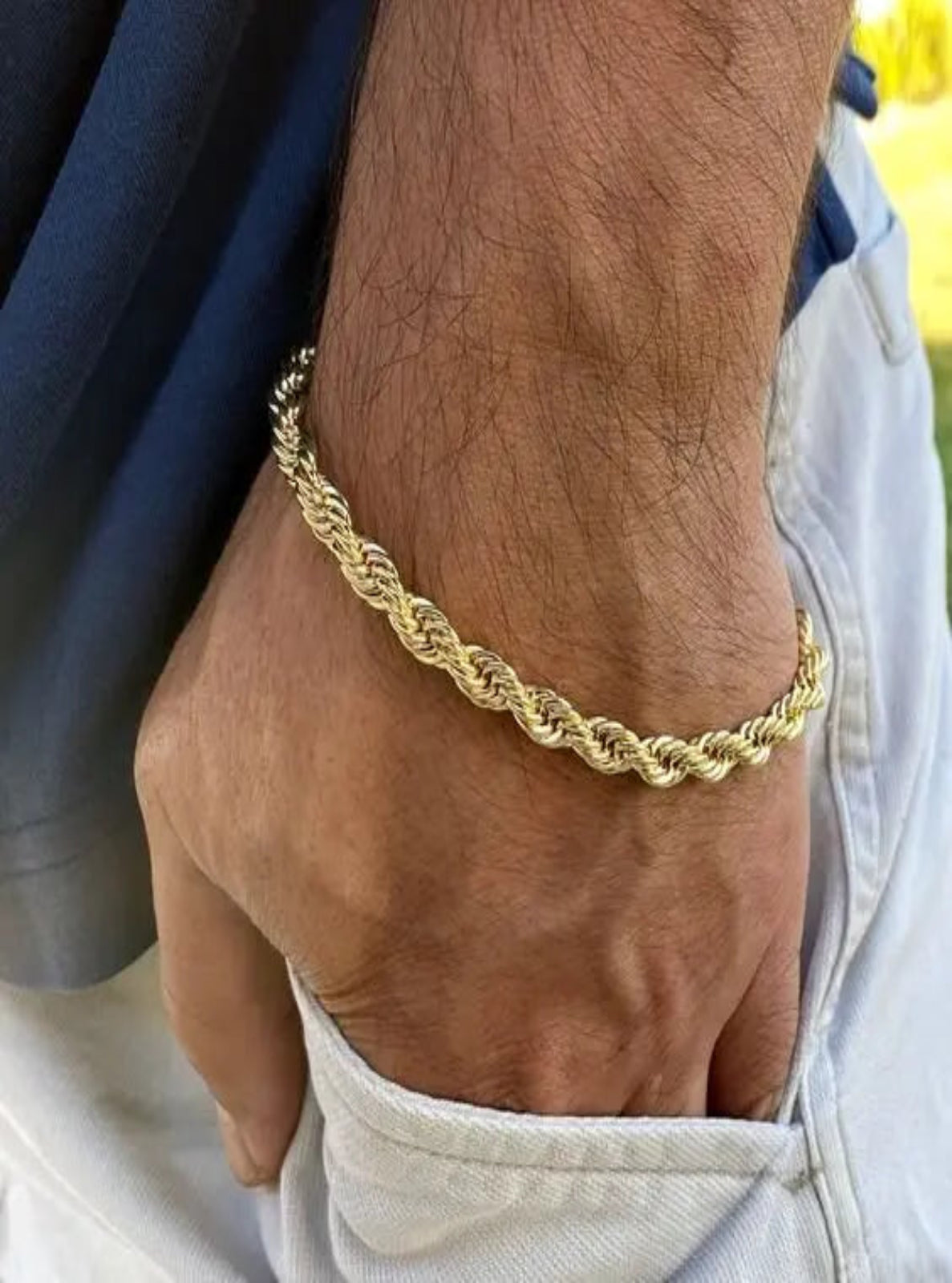 Gold rope chain bracelet on a wrist with a blurred background