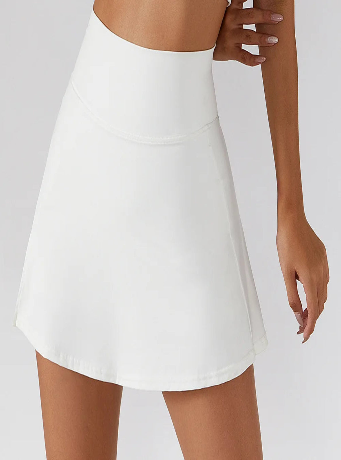 White skirt worn by a person on a plain background