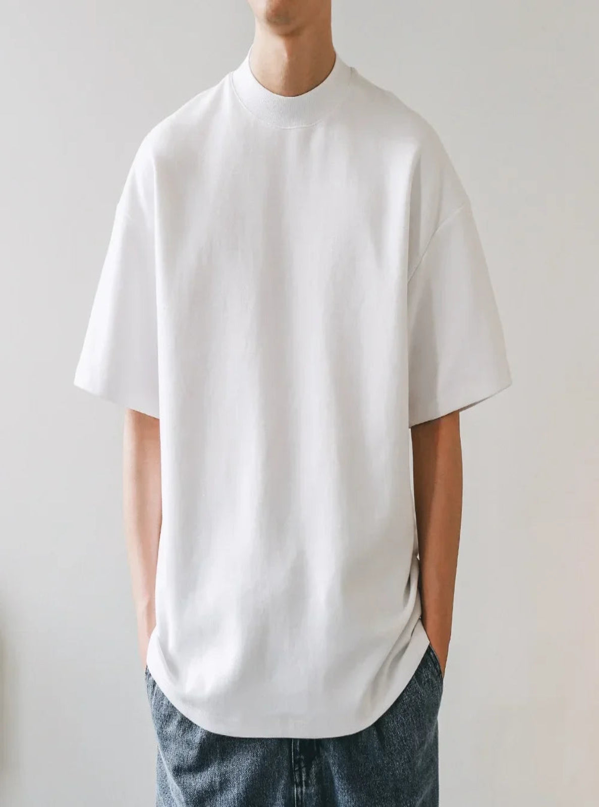 Person wearing a plain white t-shirt and blue jeans against a light gray background