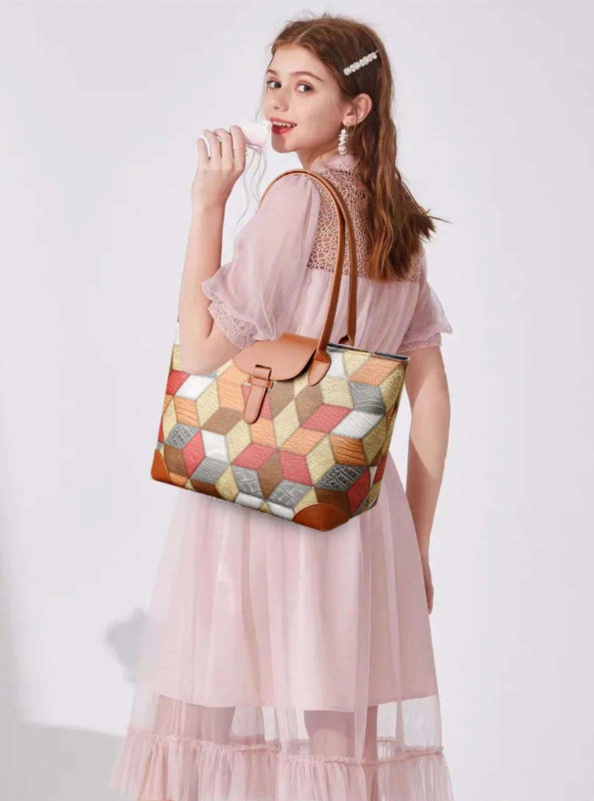 Woman holding a colorful geometric-patterned bag against a white background
