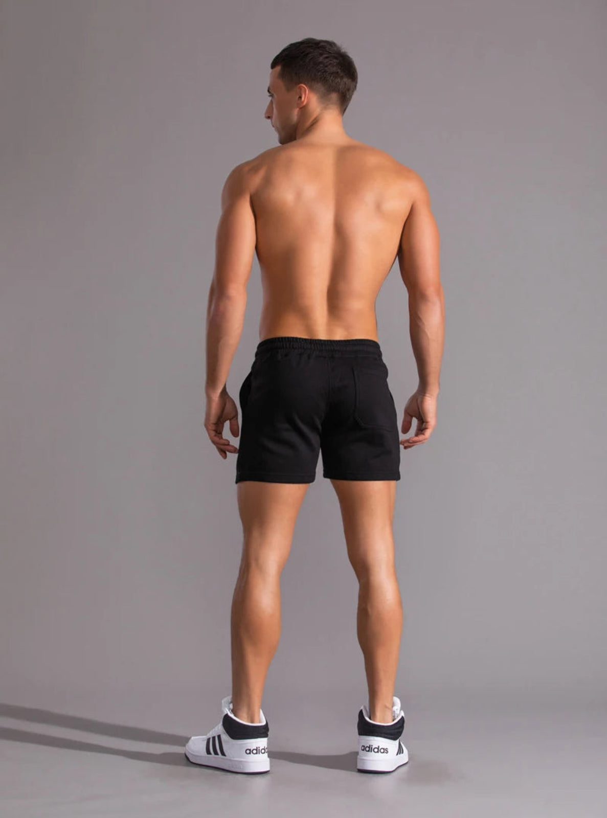 Man wearing black athletic shorts on a gray background
