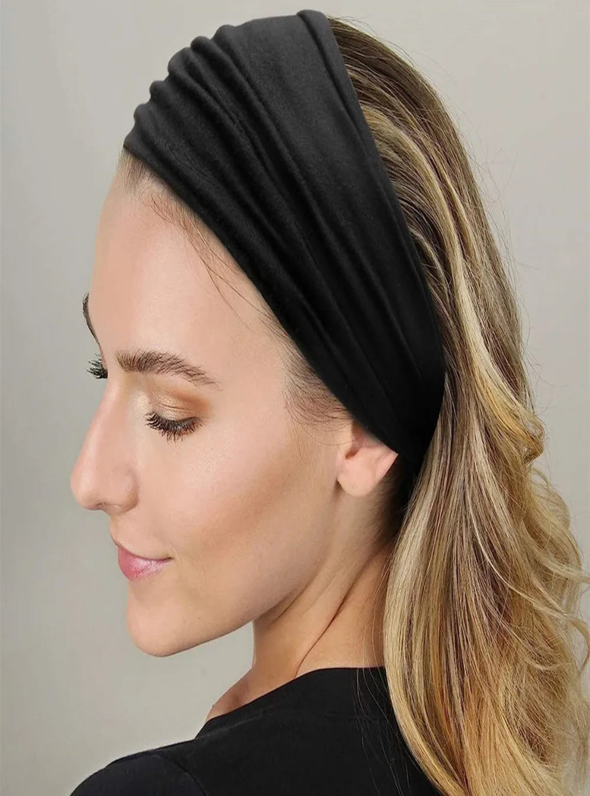 Woman wearing a black headband against a neutral background
