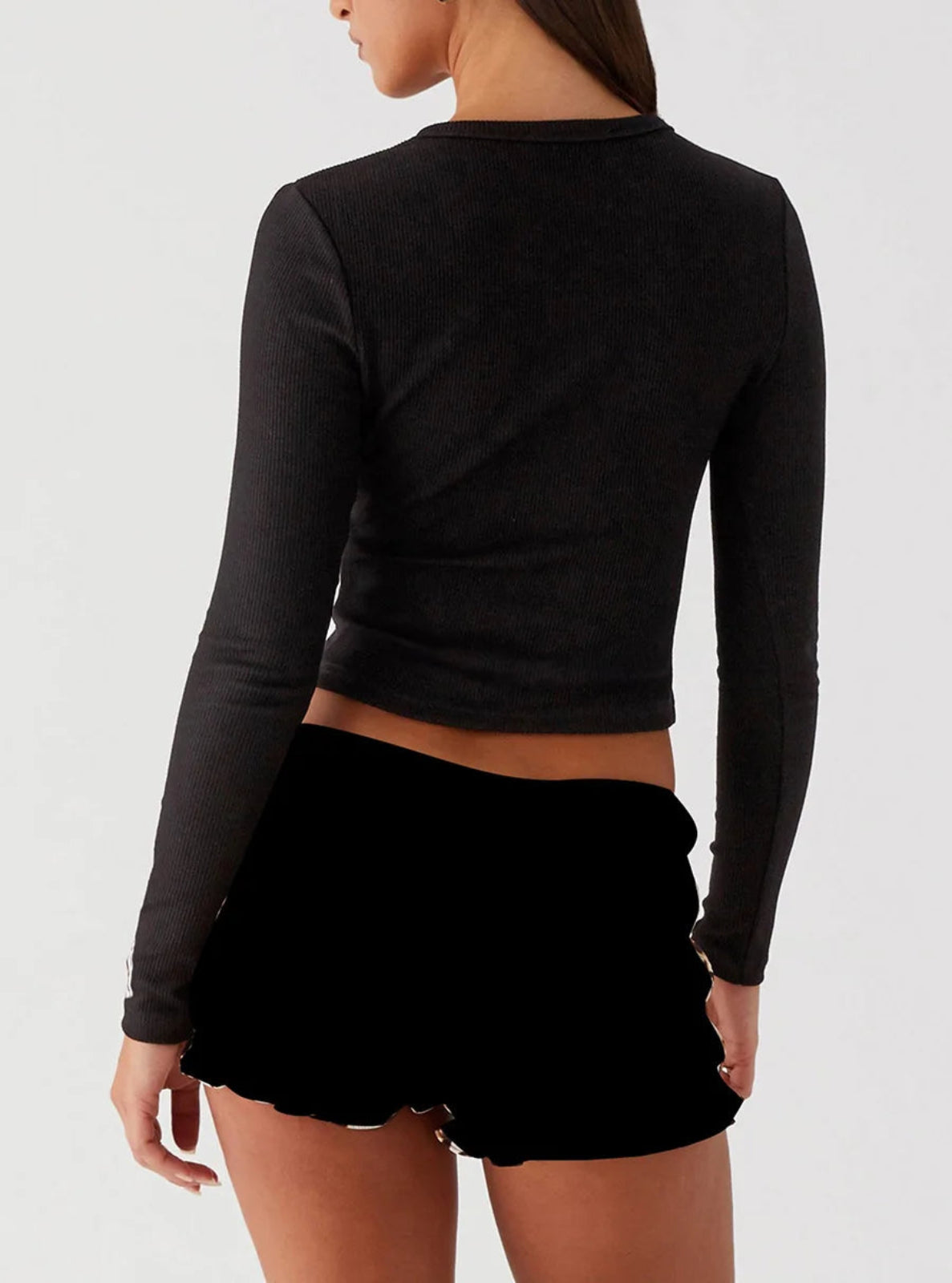 Person wearing a black cardigan and black shorts on a white background
