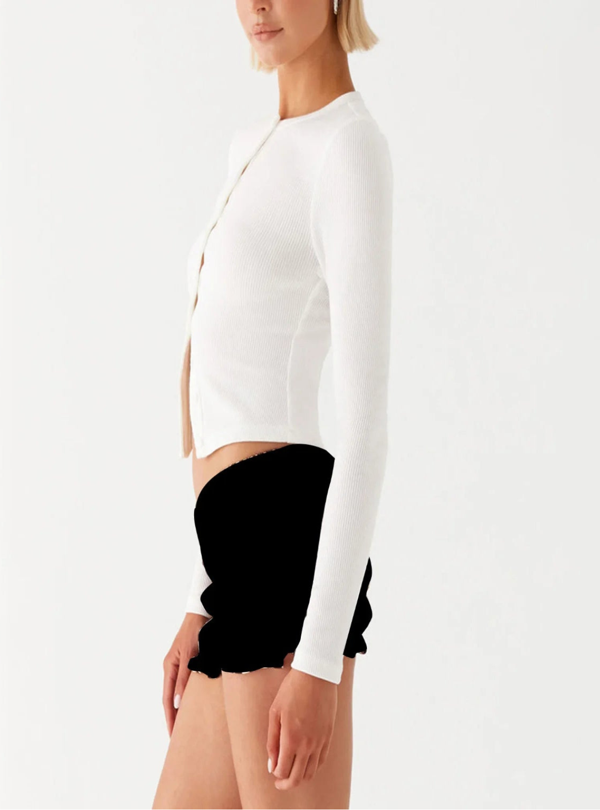 Person wearing a white cardigan and black shorts on a white background