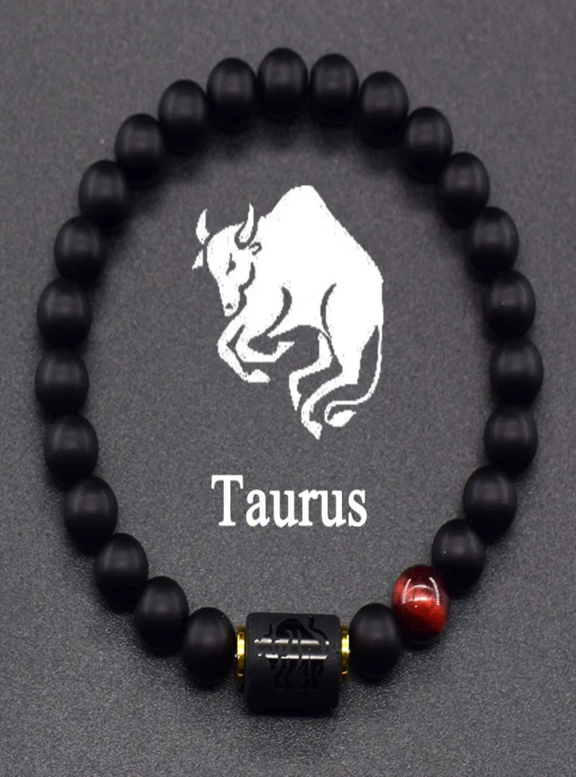 Black beaded bracelet with Taurus symbol on a gray background