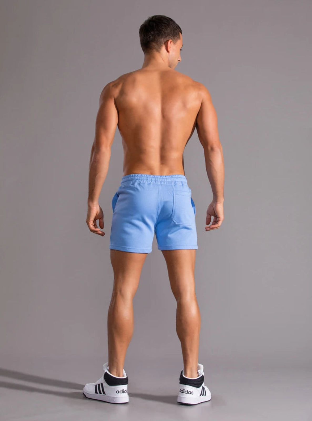 Man wearing light blue shorts on a gray background