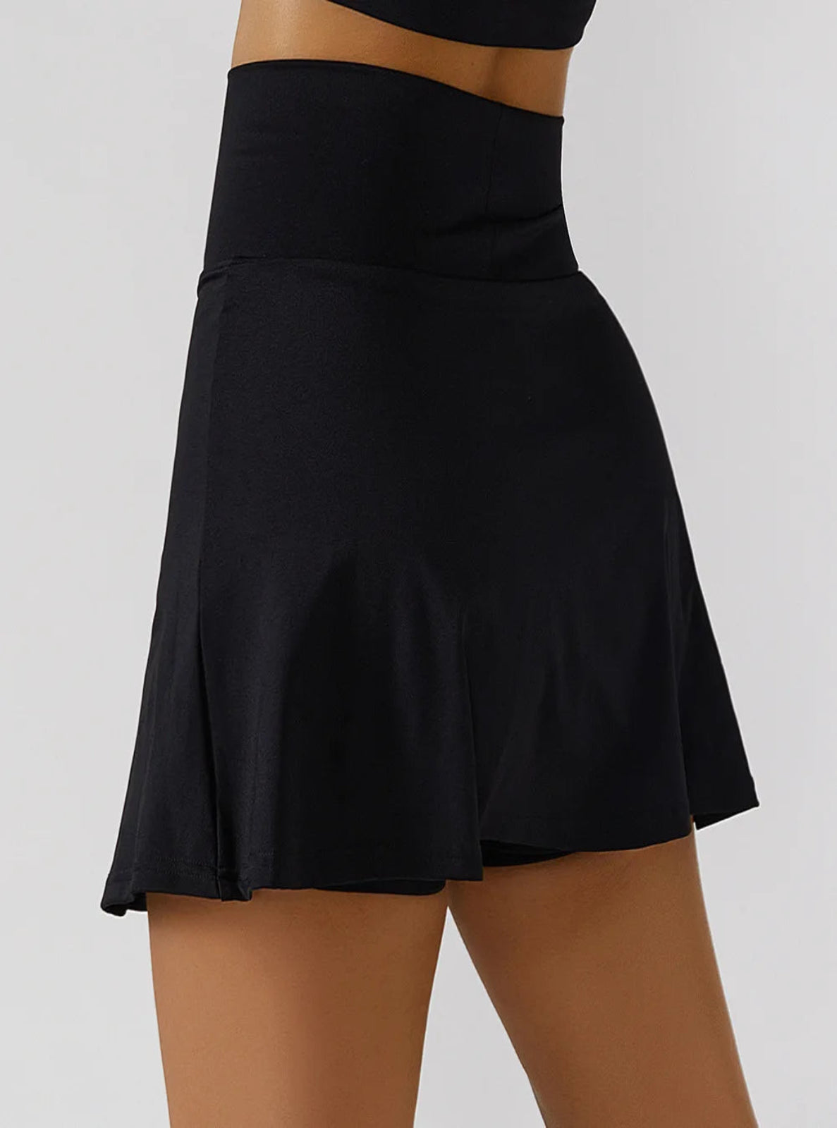 Black skirt worn by a person on a plain background