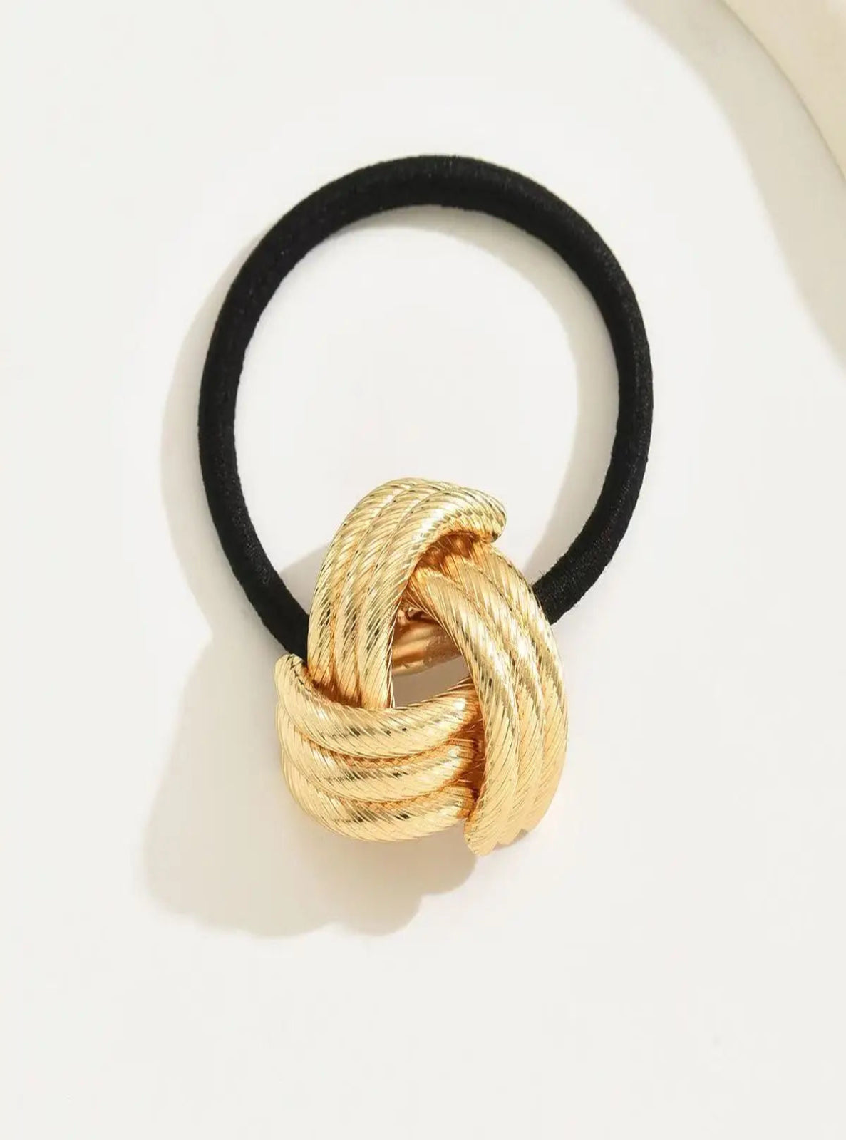 Black hair elastic with a gold knot design on a white background