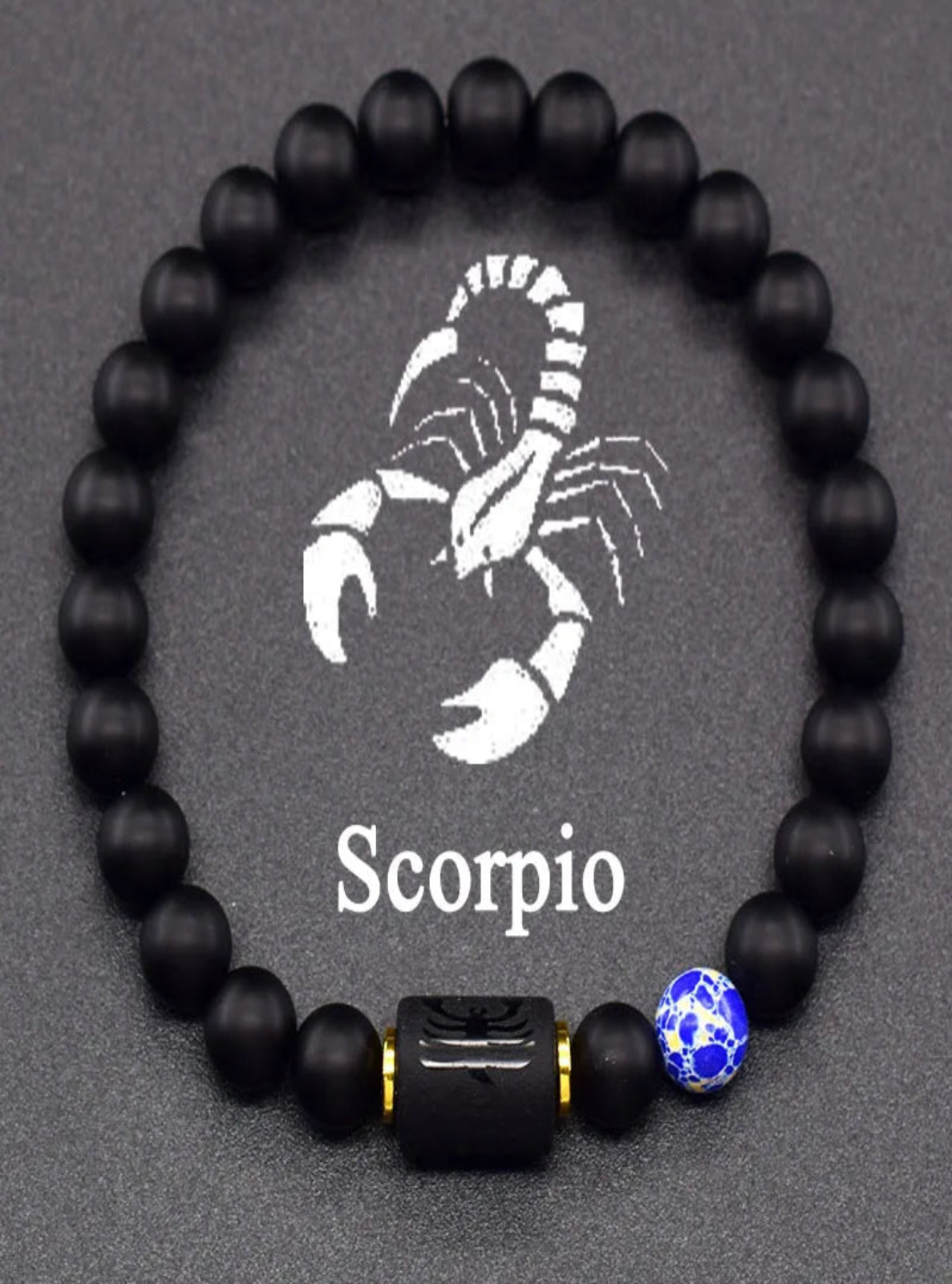 Black beaded bracelet with Scorpio symbol and blue accent bead on gray background