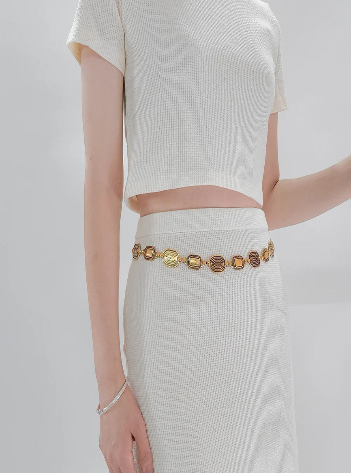 Person wearing a gold belt with a plain background