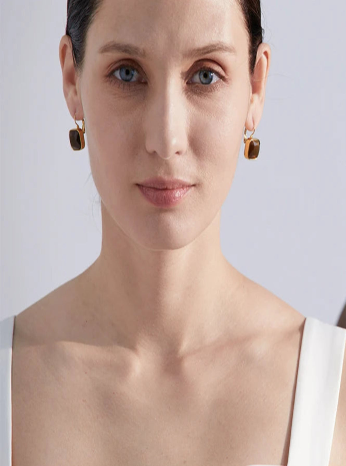 Two women wearing earrings with a plain background