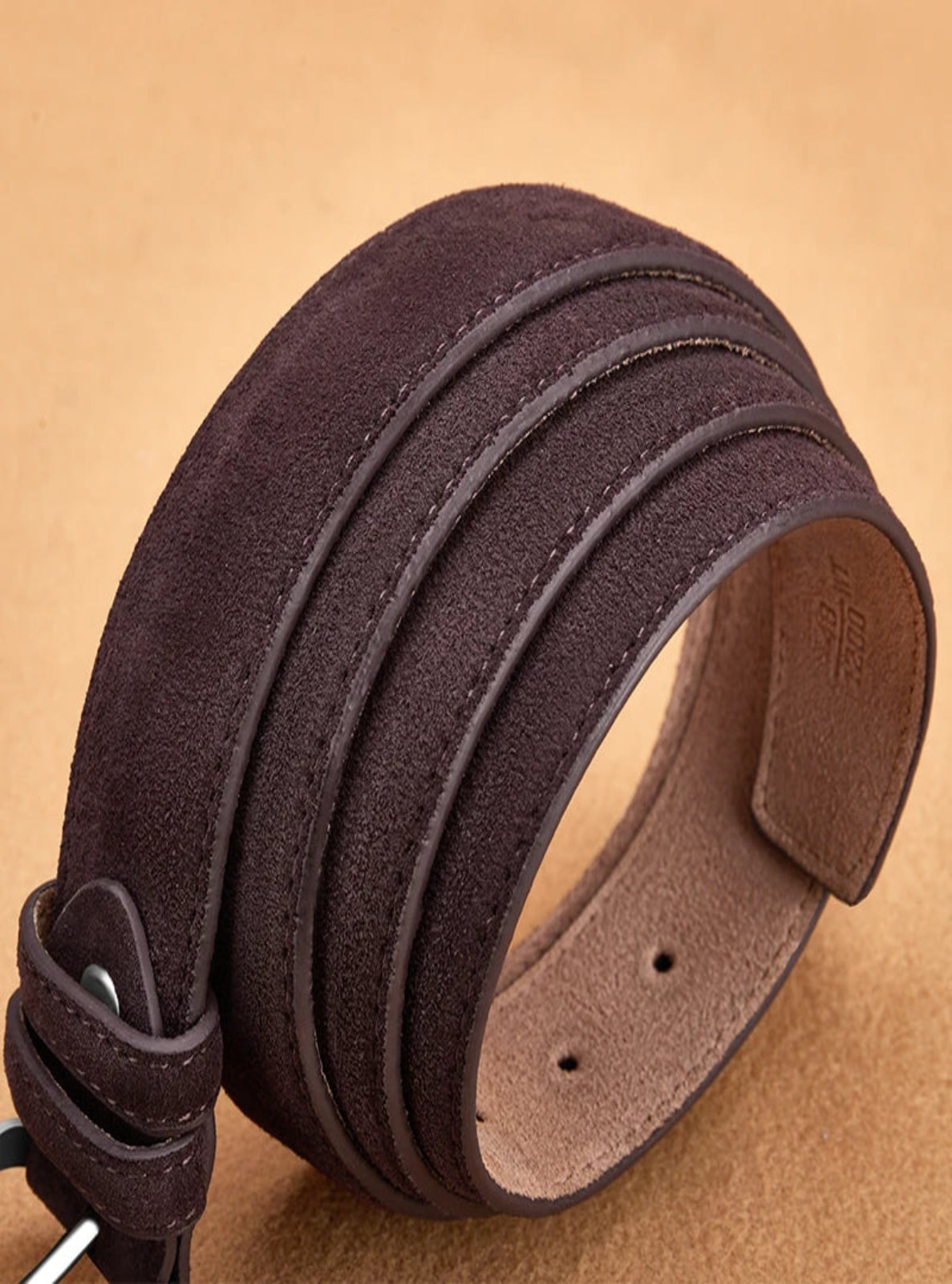Brown leather belt with a visible brand logo on a beige background